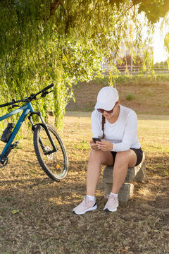 Girl checks social media on her cell phone after exercising on her bike. High quality photo