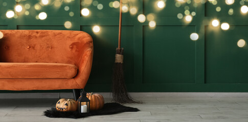 Orange sofa with Halloween decorations near green wall in room