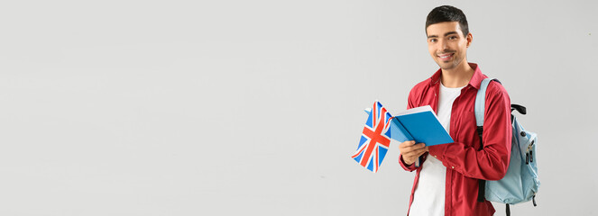 Young male student with UK flag and book on light background with space for text