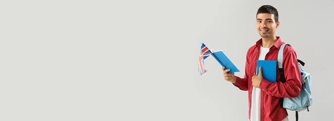 Young male student with UK flag and books on light background with space for text