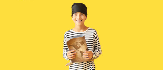 Little boy dressed as pirate with treasure map on yellow background