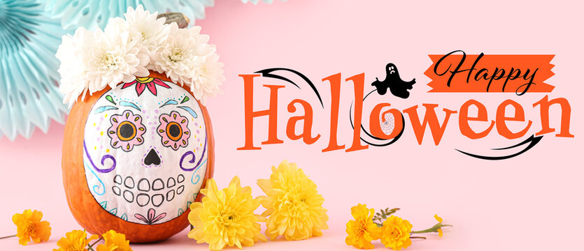 Pumpkin with painted skull and flowers on pink background. Happy Halloween