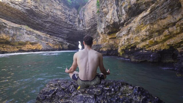 Nature lover young man meditating in seaside cave.
Young man meditating and doing yoga in the seaside bay.
