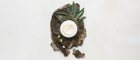 Jar of cream with olive oil extract and tree bark on white background, top view
