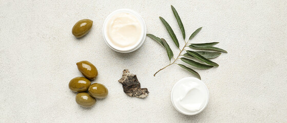 Fototapeta na wymiar Jars of cream with olive oil extract on light background, top view