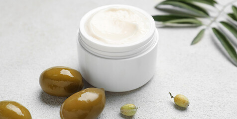 Fototapeta na wymiar Jar of cream with olive oil extract on light background, closeup