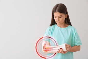 Young woman with bandage on arm against light background