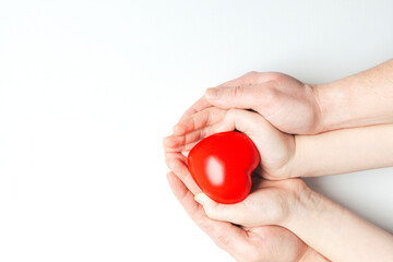 Man and child hands holding red heart on white background. Health care, love, organ donation and family insurance concept.