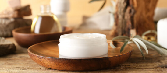 Fototapeta na wymiar Jar of cream with olive oil extract on wooden table, closeup