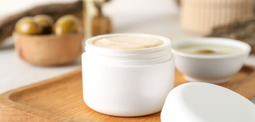 Jar of cream with olive oil extract on table, closeup
