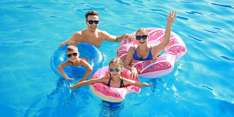 Happy family swimming in pool on summer day - Powered by Adobe