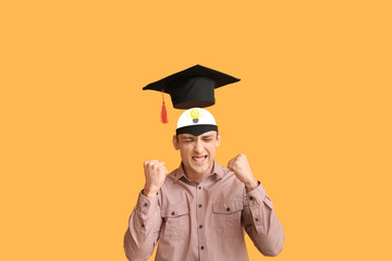 Smart man with graduation hat on orange background