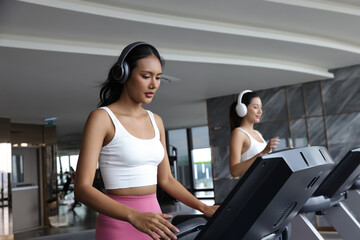 Beautiful attractive woman listening music and exercise on treadmill machine in gym fitness, urban lifestyle of healthy people . Workout exercise concept
