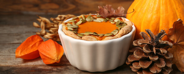 Pot with tasty pumpkin pie on wooden background