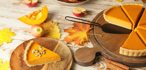 Tasty pumpkin pie and autumn leaves on wooden table
