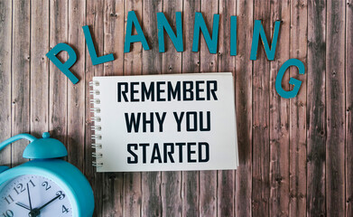 Remember why you started, text like planning on notepad and wooden table with clock