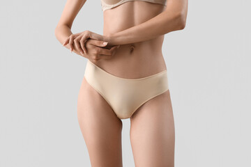Slim young woman in underwear on light background