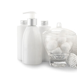 Bottles of cosmetic products and bowl with cotton balls on white background, closeup