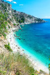 Small pebble Filikuri beach surrounded by steep high cliffs, which can only be reached from the sea. Ionian sea. Albania. Top view.