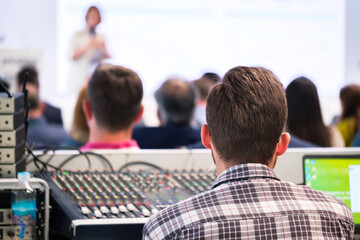 Audio video light engineer balancing and adjusting sound sources by using equalization  at a business conference or business training