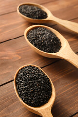 Spoons with sesame seeds on wooden background, closeup