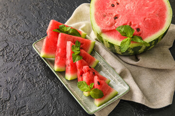 Plate with cut juicy watermelon on dark background