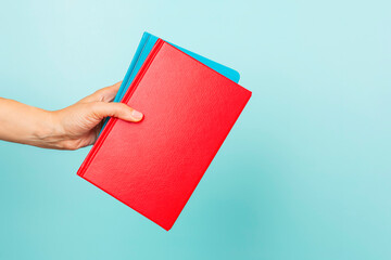 Woman hands holding books with blank cover over light blue background. Education, back to school,...