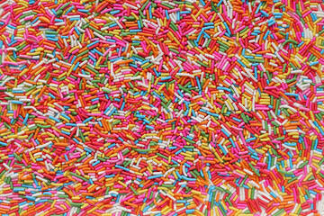 Lots of brightly colored sugar granules background used for topping desserts, cupcakes and ice cream in Top View It's a colorful background suitable for designs and has Copy Space to insert text