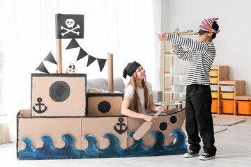 Little boy and his sister dressed as pirates playing with spyglass at home