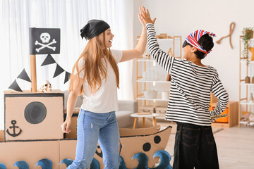 Little boy dressed as pirate playing with his sister at home