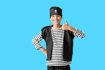 Little boy dressed as pirate showing thumb-up on blue background