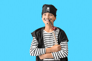 Little boy dressed as pirate with spyglass and smoking pipe on blue background