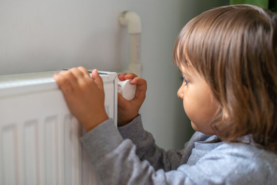 A Small Child Who Gives More Heat To The Radiator Because He Is Cold