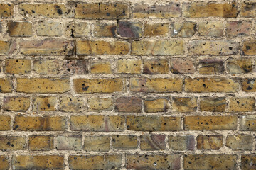 An old brick wall with old bricks of yellow and gray hue. The brick wall of a London street. 
