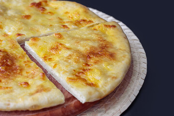 close-up cut piece of georgian khachapuri on a wooden kitchen board on a dark table. National traditional Georgian cuisine. front view
