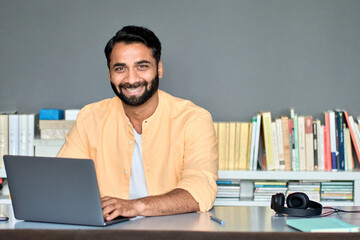 Happy indian business man remote teacher, eastern professional manager using laptop computer in...