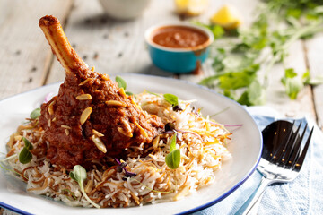 roasted lamb shank biryani with sauce served in a dish side view isolared on wooden table