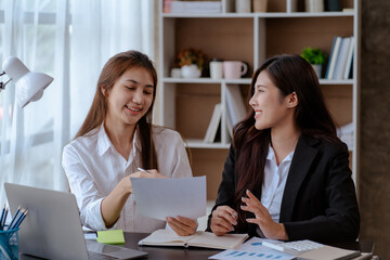 Happy young Asian businesswoman sitting on her workplace in the office. Young woman working at laptop computer in the office