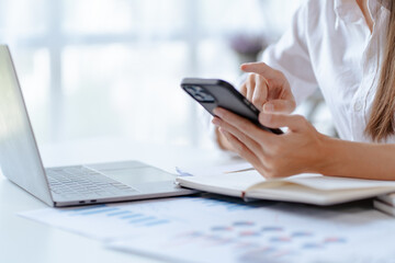 Happy young Asian businesswoman sitting on her workplace in the office. Young woman working at laptop computer in the office