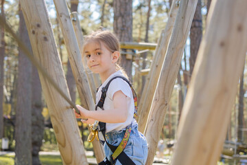 happy little girl in a rope park on the wood background.