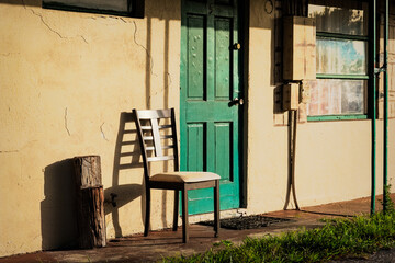 Chair in sunlight next to the door of a cheap motel room