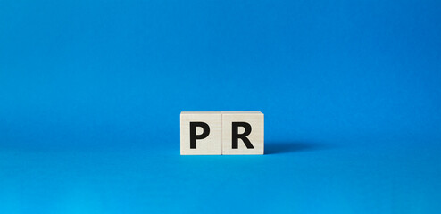 PR - Public Relations symbol. Concept word PR on wooden cubes. Beautiful blue background. Business...