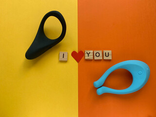 Sex shop assortment. Black cock ring and vibrator. Lettering I LOVE YOU. Orange background. Useful...