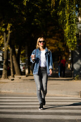 Fototapeta premium girl in a denim jacket with coffee in her hands crosses