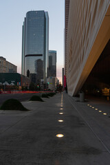 Obraz premium Sidewalk lights and car trails lead into the Los Angeles skyline