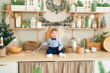 a toddler boy sits on the countertop of the kitchen decorated for the new year.