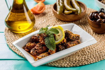Hot and spicy Chicken Wings with lime and pickle served in a dish isolated on cutting board side view