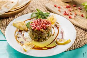 Baba Ghanouj with lemon slice served in a dish isolated on cutting board side view