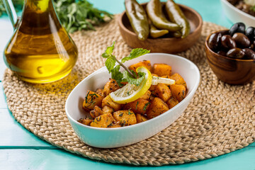 Batata Harra or potatoes served in a dish isolated on cutting board side view