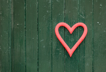 red heart shape in front of a textured green door, close up, love concept